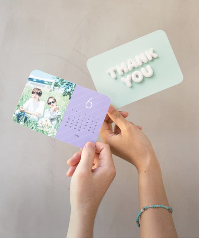 写真カレンダーとThank Youカードを手に持つ様子